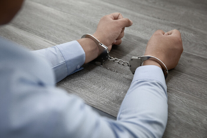 selective-focus-shot-male-hands-handcuffs-wooden-table700.jpg